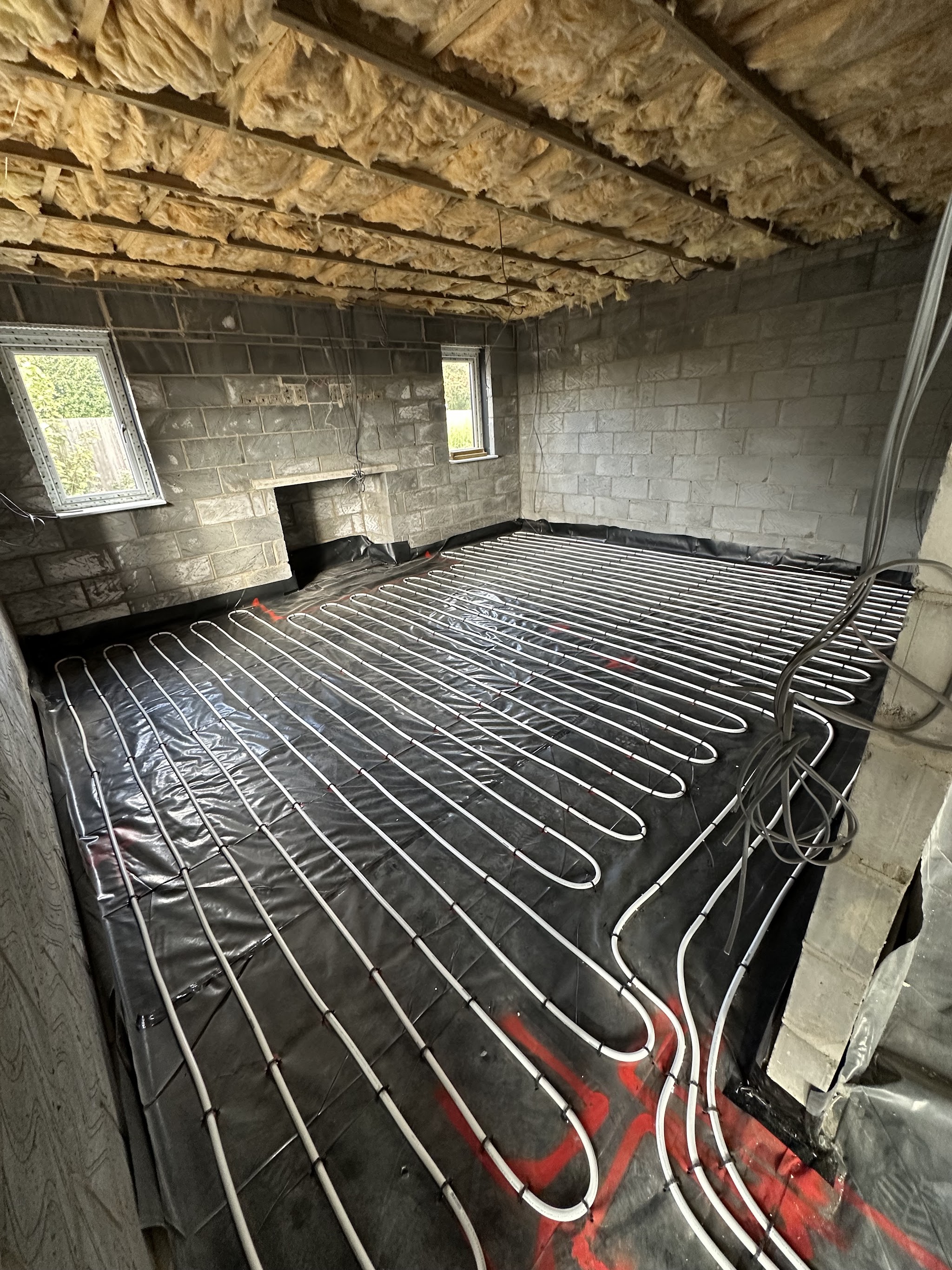 Heating pipework laid across the floor of a new block-built room