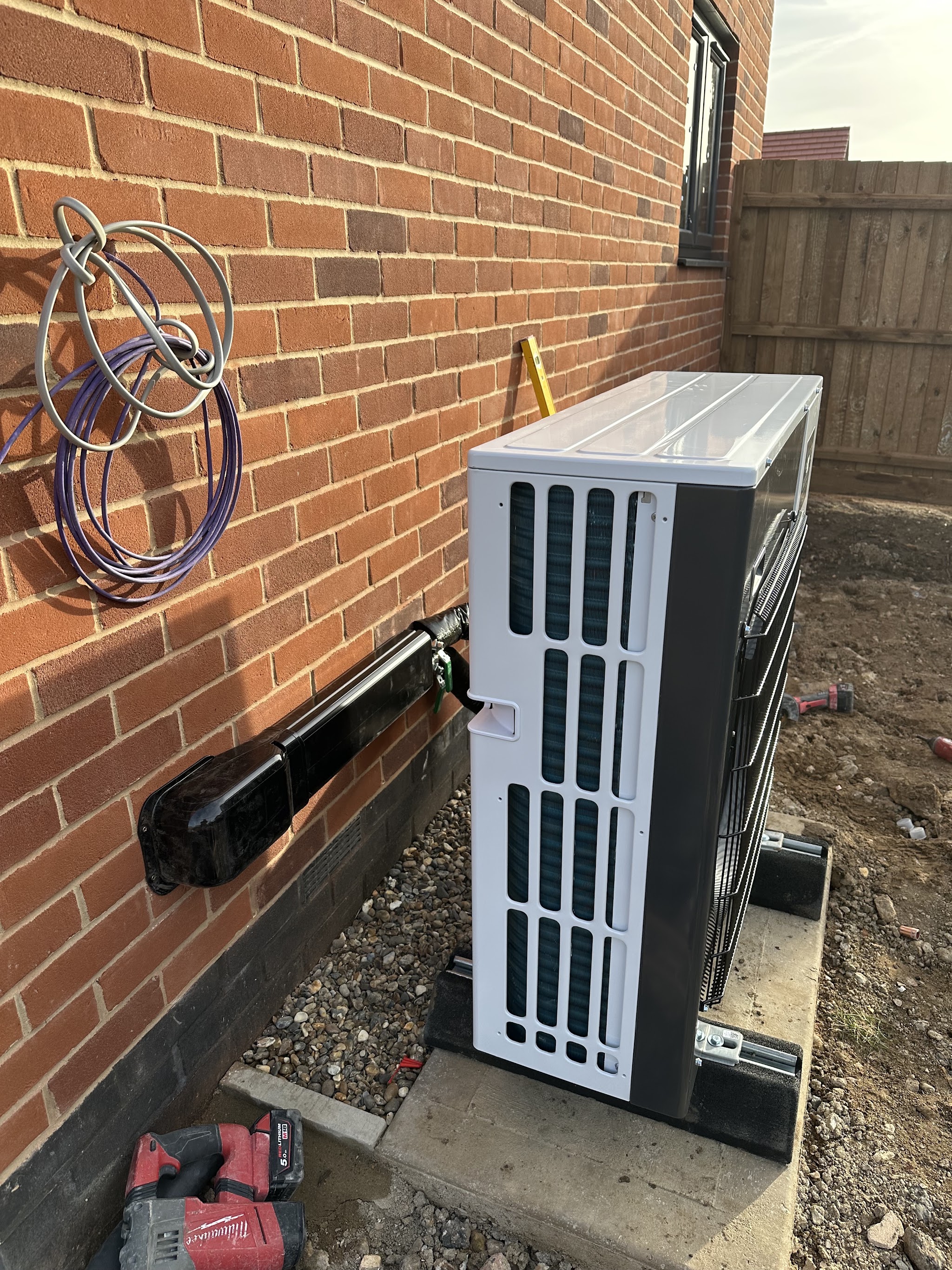 Air source heat pump outdoor unit mounted against a brick wall