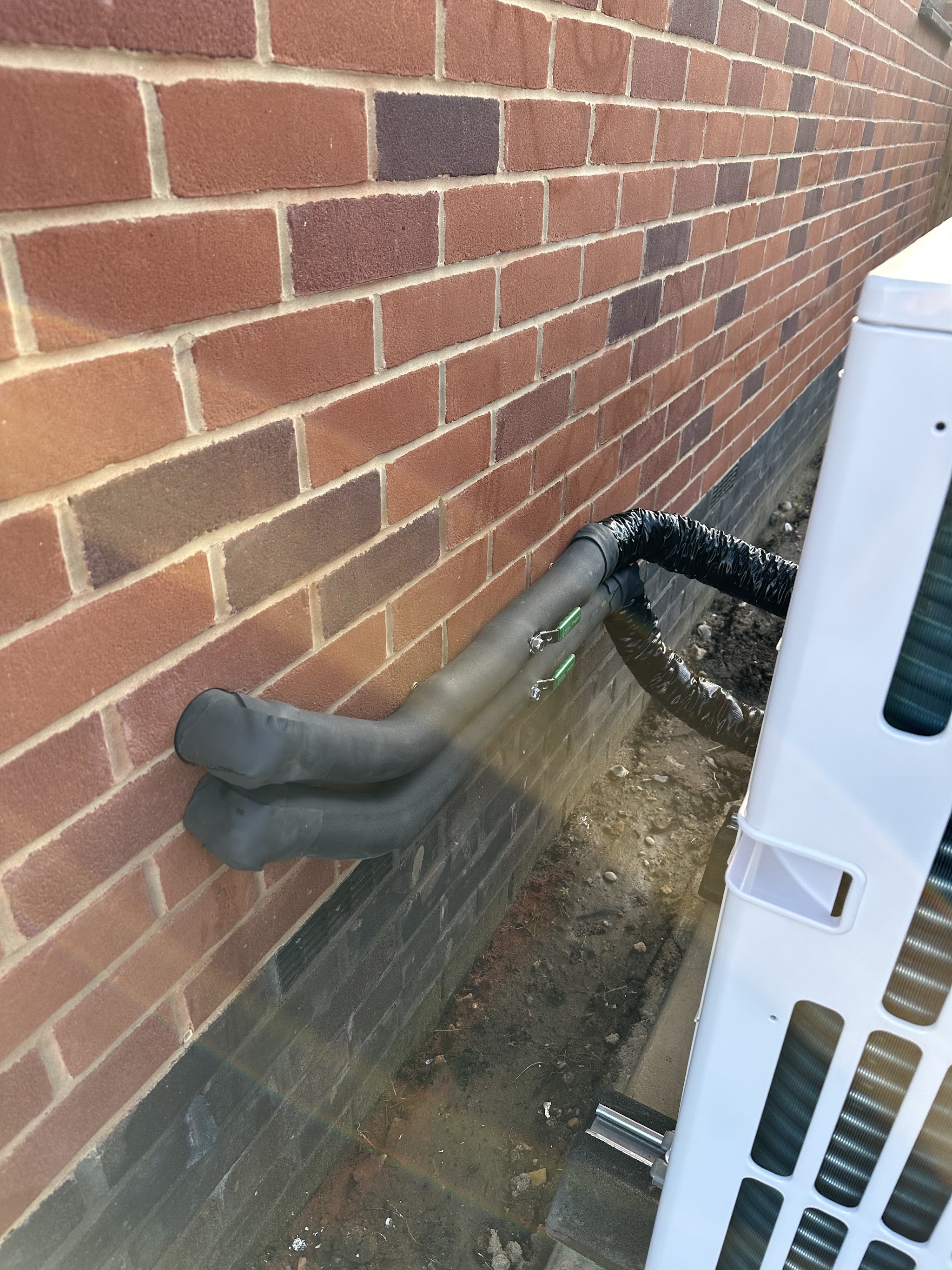 Insulated pipe run behind an outdoor heat pump unit